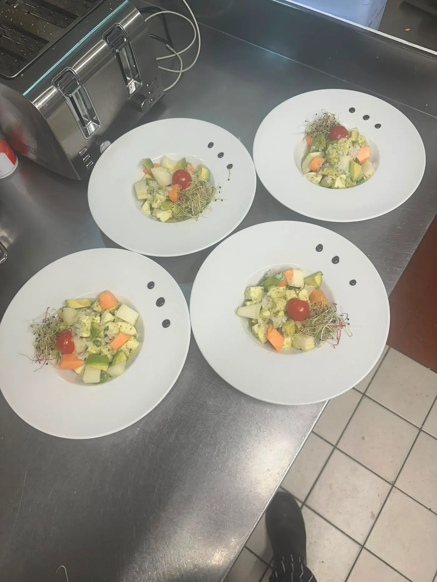 Quatre assiettes de tartare dressées côte à côte au passe