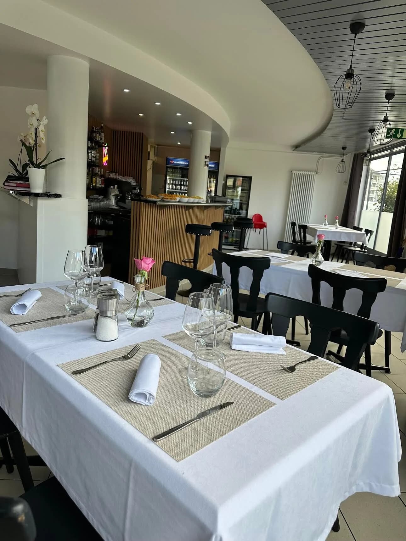 La salle du Prestige, tables dressées de nappes blanches devant le bar en bois