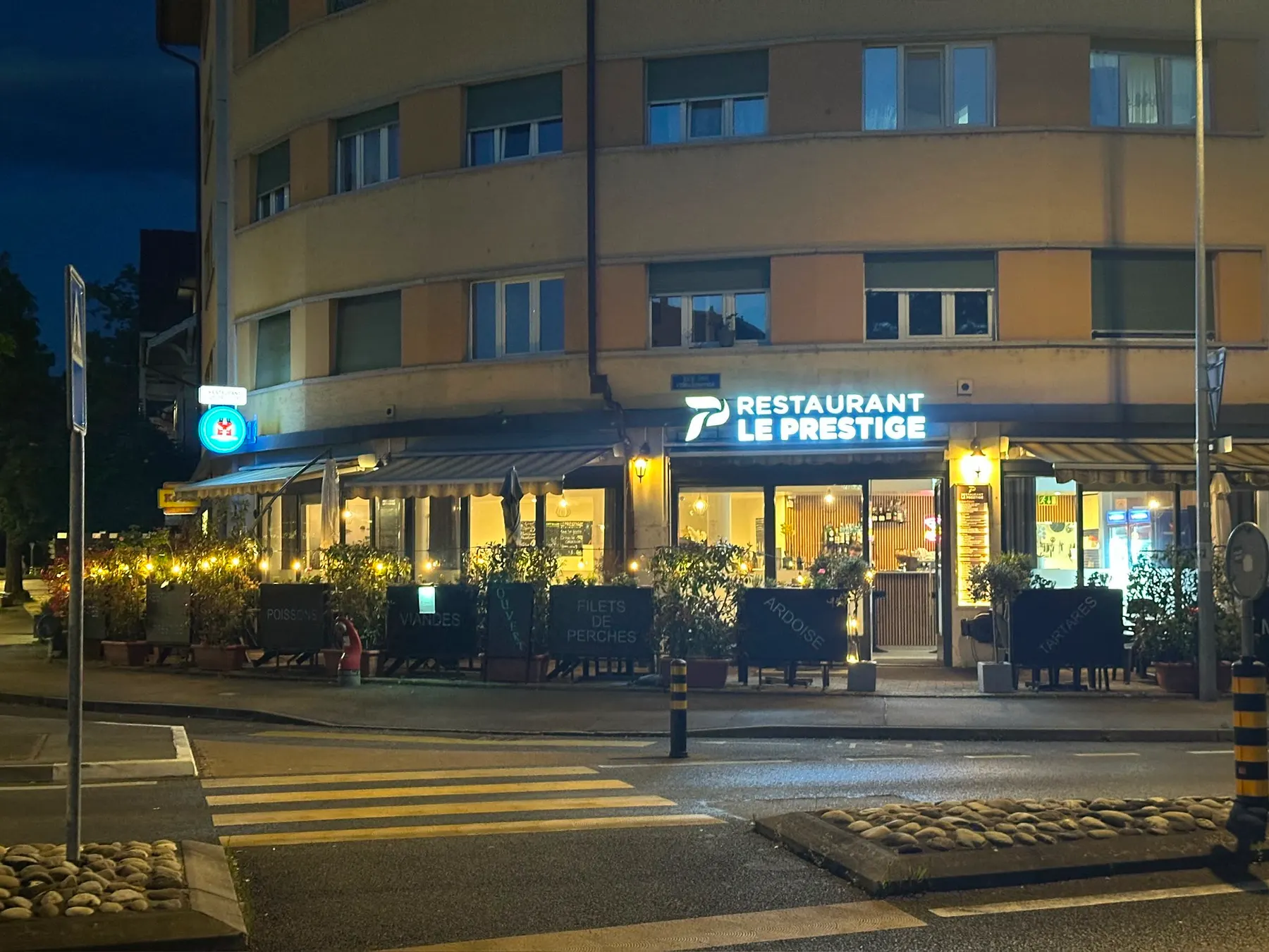 Die Fassade des Prestige bei Nacht, vom Fussgängerstreifen aus gesehen, das Schild beleuchtet