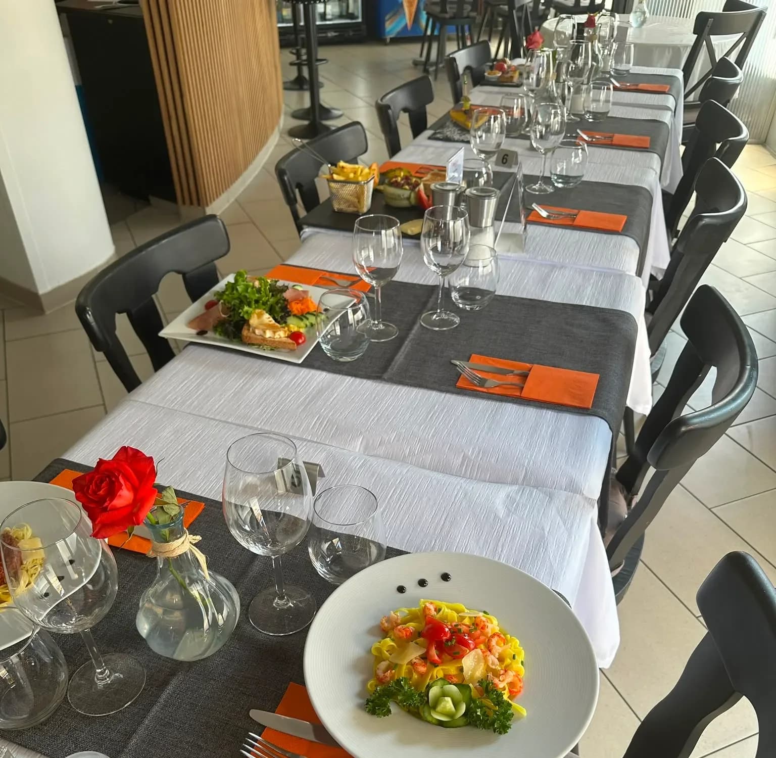 The dining room set table after table, white tablecloths and orange napkins