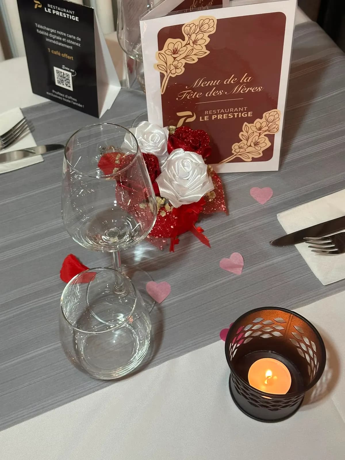 A table set for an occasion, with a candle and red petals