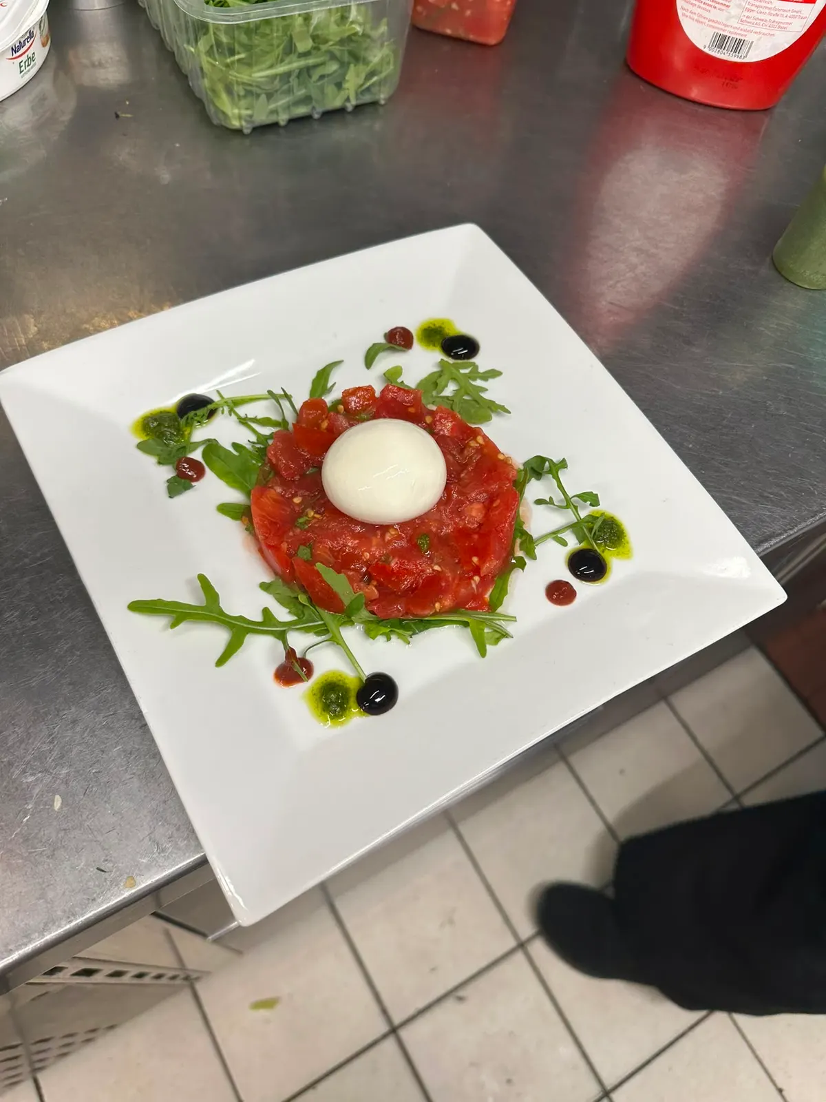 Ein rund angerichtetes Tartare, Eigelb in der Mitte, auf einem weissen quadratischen Teller