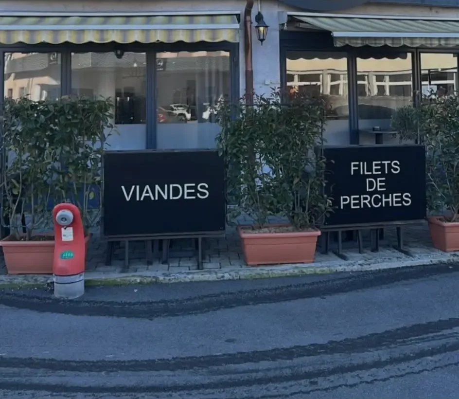 Die Front des Restaurants, zwei bemalte Tafeln «Viandes» und «Filets de perches» vor den Fenstern